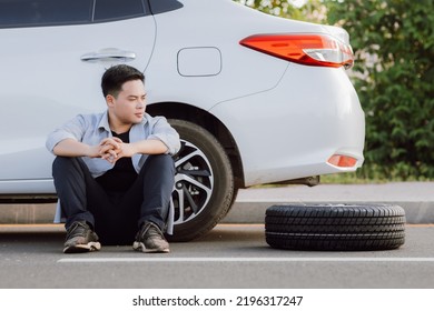 Asian Young Man Failed To Fix A Problem On The Road, Car Broke Down Or Changing Flat Tire On The Road Concept.