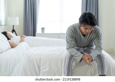 Asian young man feel angry girlfriend having conflict domestic problem. New marriage man and woman feel heartbroken for quarrel conflict while sit on bed in bedroom. Family problem-separation concept.