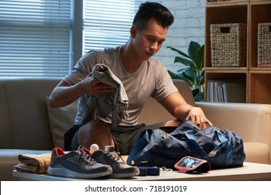 Asian Young Man Filling Bag With Stuff For The Gym