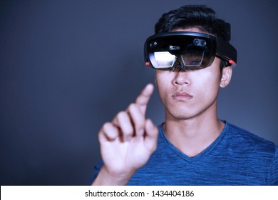 The Asian young man with glasses of virtual reality. Experience VR hololens headset in studio with advanced technology.