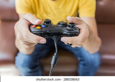 An Asian young man holding game controller playing video games