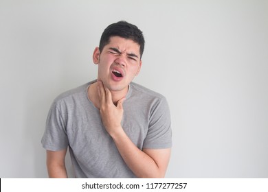 asian young man holding his neck and making hurting face on white background