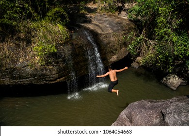 Asian young man jump off the cliff into river - Powered by Shutterstock