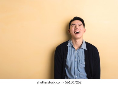 Asian Young Man Laughing In The Studio Yellow Background