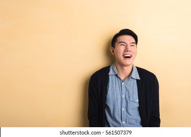 Asian Young Man Laughing In The Studio Yellow Background