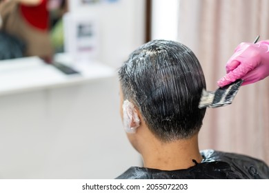 Asian Young Man Making A Hair Dye At Hair Salon And Spa. Professional Hair Stylist Coloring - Dying Hair In Male Salon.