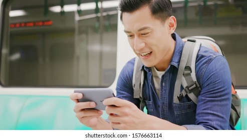 Asian Young Man Play Game With 5g Smartphone In The Metro