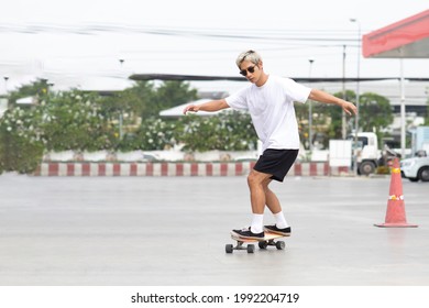 Asian Young Man Playing Surfskate Or Skate Board In Gas Station Urban City Outdoor. Extream Sports 