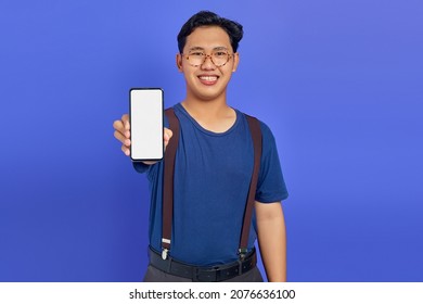 Asian Young Man Showing Blank Smartphone Screen With Hand To Camera On Purple Background