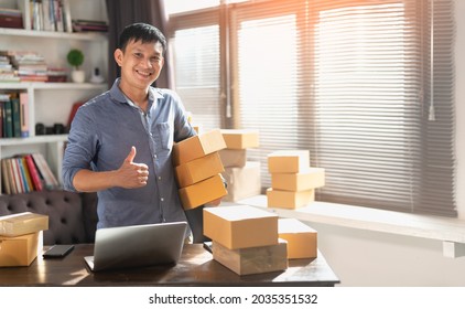 Asian Young Man Start Small Business In A Cardboard Box At Work. The Seller Prepares The Delivery Box For The Customer, Online Sales, Or Ecommerce.