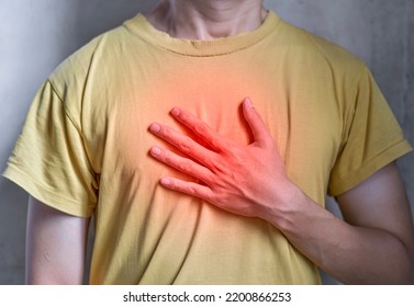 Asian Young Man Suffering From Central Chest Pain. Chest Pain Can Be Caused By Heart Attack, Myocardial Infarct Or Ischemia, Myocarditis, Pneumonia, Oesophagitis, Stress, Etc,.