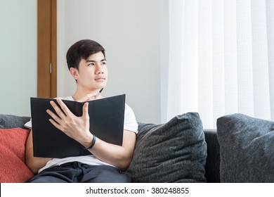 Asian Young Man Thinking And Wondering While Writing A Paper At Home