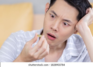 asian young man unhappy frustrated bored taking medicine.