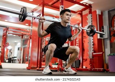 Asian young man using dumbbell Pushing up exercise at gym for good healthy in fitness, Lifestyle and sport exercise concept.  - Powered by Shutterstock