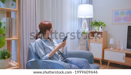 asian young man using smart home app to control light colors by cellphone in the evening at home