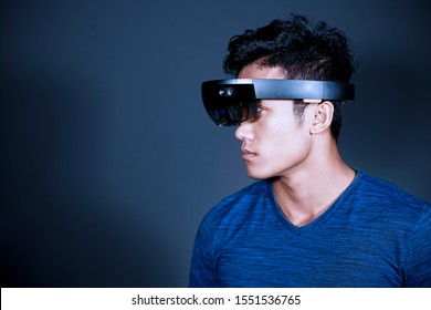 The Asian young man with virtual reality glasses. Experience VR hololens headset in studio with advanced technology.