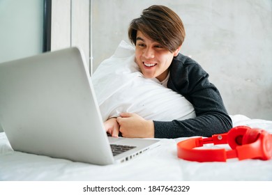 Asian Young Man Watching Movie In Bedroom In The Morning.