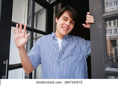 Asian Young Man Waving Hand At Camera At Front Door.