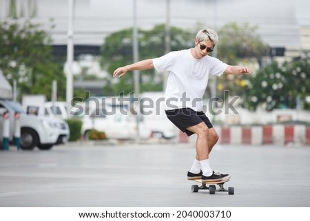 asian young man wear sunglasses playing skateboard on street city.  skateboarding outdoor sports.