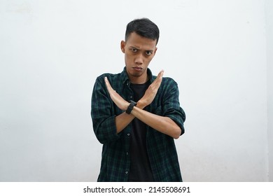 Asian young man wearing dark green casual clothes on white background doing stop singing with palms. A warning expression with a negative and serious attitude on the face.