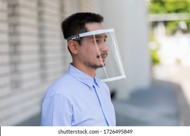 Asian Young Man Wearing Face Shield For Healthcare Which Is Required For Doctor And General Public To Prevent COVID-19.