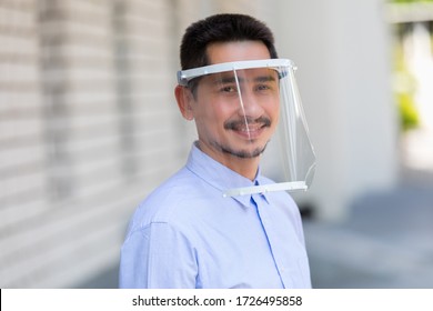 Asian Young Man Wearing Face Shield For Healthcare Which Is Required For Doctor And General Public To Prevent COVID-19.