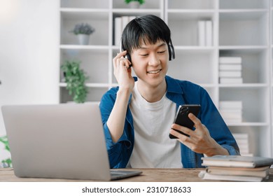 Asian young man wearing headphones to listen to music happy and relax. - Shutterstock ID 2310718633