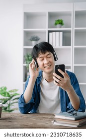 Asian young man wearing headphones to listen to music happy and relax. - Shutterstock ID 2310718635