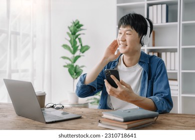 Asian young man wearing headphones to listen to music happy and relax. - Shutterstock ID 2310718641