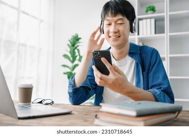 Asian young man wearing headphones to listen to music happy and relax. - Shutterstock ID 2310718645
