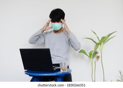 Asian Young Man Wearing A Mask Sitting In Front Of A Laptop Dizzy With His Job