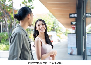 Asian Young Man And Woman Shopping Goods Outdoors In Department Store. Attractive Couple Hold Shopping Bags Then Walking Together With Happiness, Enjoy Purchasing In Shopping Mall Marketplace Center.