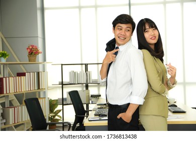 Asian Young Man And Woman Stand Smiling, Satisfied With  The Successful Working In Their Office, Startup And Bussiness Owner.