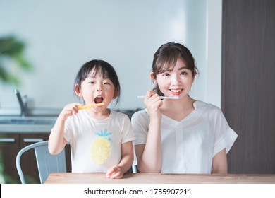 Asian Young Mom And Daughter Brushing Teeth In The Room