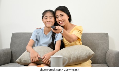 Asian Young Mom Watching TV With Her Lovely Daughter In The Comfortable Living Room. Family Activity Concept.