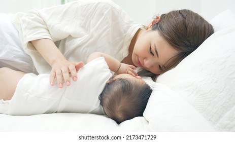 Asian young mother and a baby lying on a bed. Child rearing. Newborn.