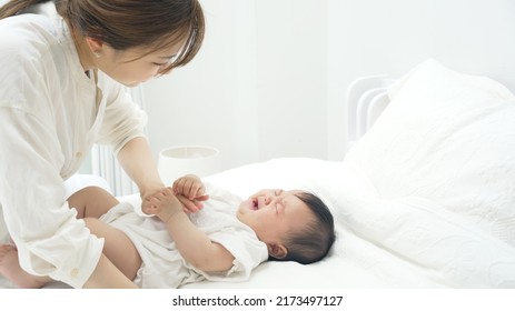 Asian young mother and a baby lying on a bed. Child rearing. Newborn.