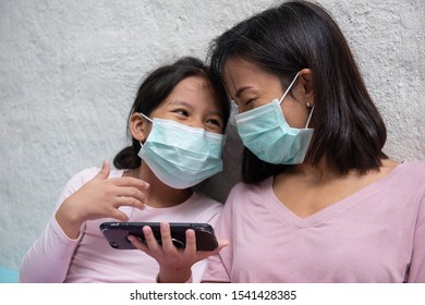 Asian Young Mother And Children Daughter Wearing Protective Mask, Use Internet Smartphone, Difficulty Swallow, Cold, Flu Or Fever Go To The Hospital Meet A Doctor