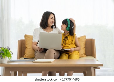 Asian young mother with computer notebook teaching kid to learn or study online at home, Homeschooling online concept - Shutterstock ID 1797044695