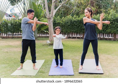 Asian Young Mother, Father And Child Daughter Practicing Exercising Stretching Together Before Yoga Workout Outdoor Morning In Nature A Field Garden Park. Happy Family Kid Sport Healthy Lifestyle