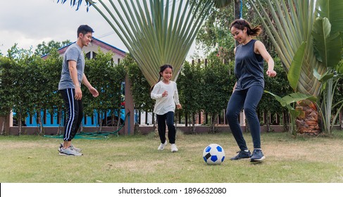 Asian Young Mother, Father And Child Daughter Playing Soccer Outside In Nature A Field Garden Park. Happy Family Kid Funny Play Football Together In Summer, Sport And Exercises For Healthy Lifestyle