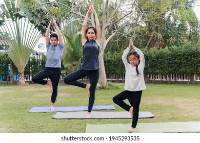 Asian Young Mother, Father Practicing Doing Yoga Exercises With Child Daughter Outdoors In Meditate Pose Together In Nature A Field Garden Park, Family Kid Sport And Exercises For Healthy Lifestyle