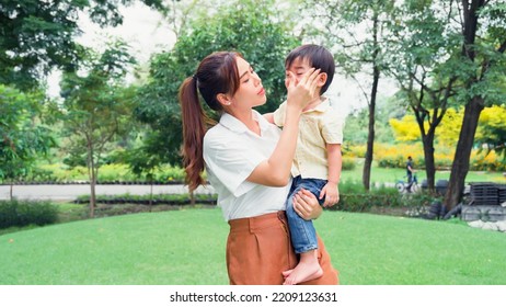 Asian Young Mother Holding A Little Son Of Her Being Irritable And Overbearing In Park.