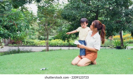 Asian Young Mother Holding A Little Son Of Her Being Irritable And Overbearing In Park.