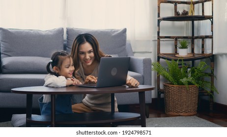 Asian Young Mother With Laptop Computer Teaching Her Kid To Learn Or Study Online In Living Room At Home, Mum And Little Preschool Daughter Learning Online On Computer, Family Homeschooling Online