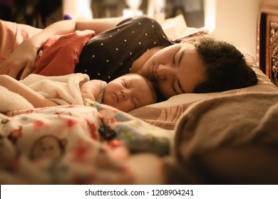 Asian Young Mother Sleeping With Her Baby, Holding Him In Her Arms From Happiness At Night.