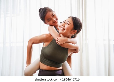 Asian young mother teaching her daughter to yoga pose and exercise together on yoga mat in living room at home. New normal lifestyle concept. Healthy lifestyle. Relaxing at home - Powered by Shutterstock