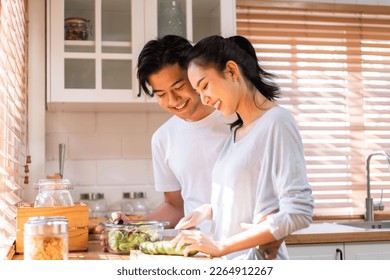 Asian young new marriage couple spend time together in kitchen at home. Attractive man and woman feeling happy and relax, enjoy cooking foods for breakfast with happiness. Family relationship concept. - Powered by Shutterstock