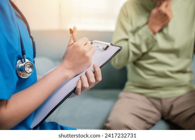 Asian young nurse checking senior man neck pain in clinic at retirement home, doctor woman examines lymph nodes on neck to determine if swollen, sore throat - Powered by Shutterstock