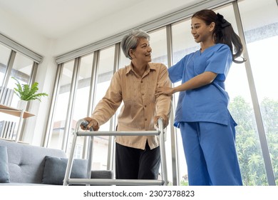 Asian Young physical therapist female help aged female patient walk with walker at home, aftercare and physiotherapy concept - Powered by Shutterstock